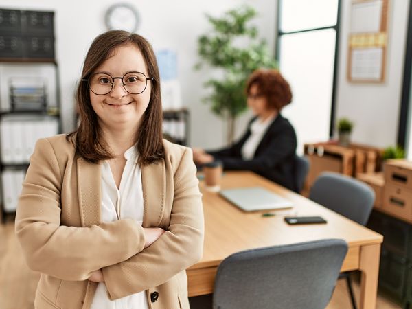 Down syndrome girl working at inclusive teamwork. Group of two women working at the office