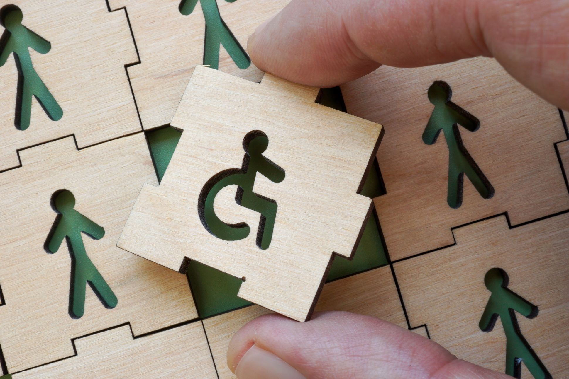 Hand holding puzzle piece with disability symbol. Concept of inclusion in work and society.